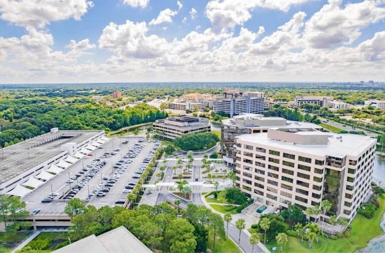 Aerial view showcasing modern office buildings amidst a bustling cityscape, highlighting a parcel of property in Tampa, Florida.