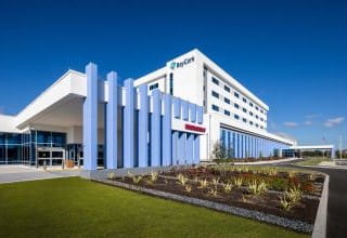 Exterior view of BayCare Hospital Wesley Chapel on a sunny day, featuring modern architectural design with large vertical columns and landscaped grounds.