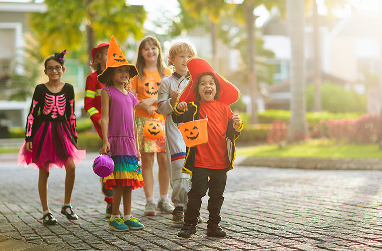 A group of children dressed in Halloween costumes standing together. 