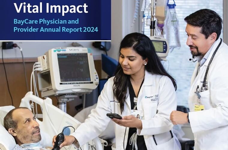 A female physician and male physician are treating a male patient in his hospital room.