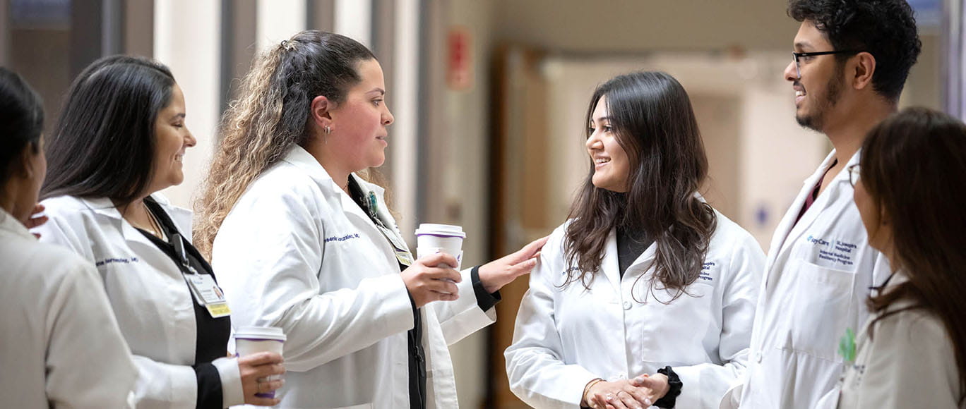 A group of six BayCare residents stand in a circle and talk to each other.
