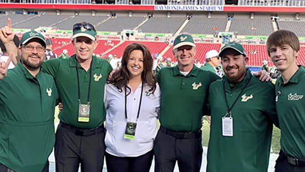 A group of faculty and fellows from the Sports Medicine Fellowship program smile for a photo on the floor of Raymond James Stadium.