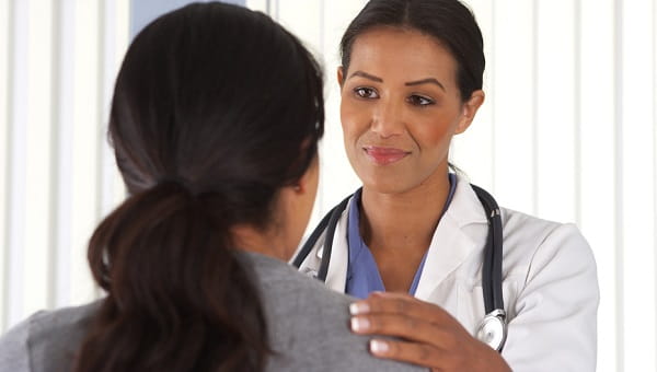 young female doctor placing her hand on her patients shoulder