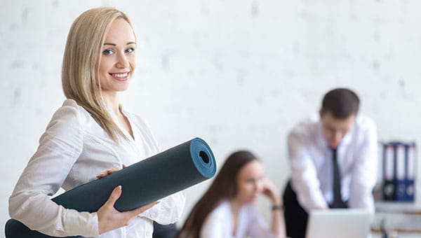 Female walking through an office with a yoga mat