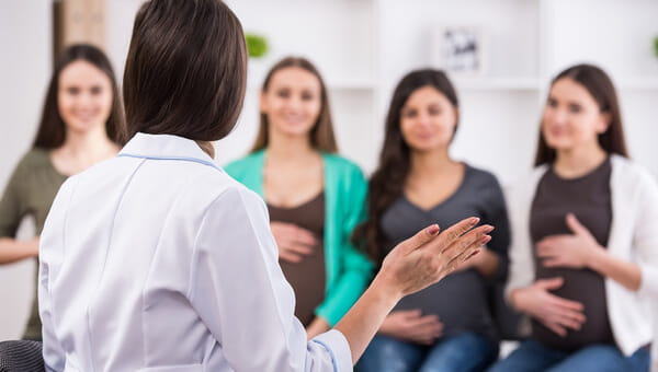 pregnant women listening to a doctor in a classroom setting