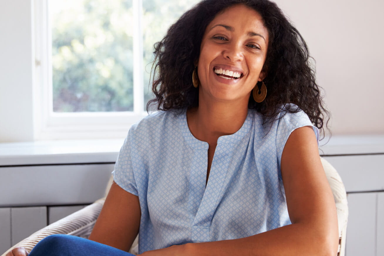 a woman sitting down in her room and smiling