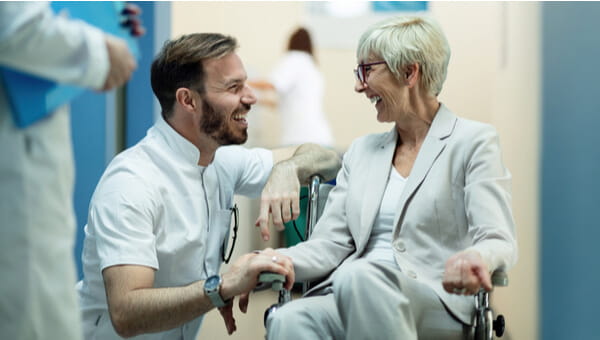 a man kneels and speaking with an elderly woman