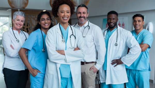 team of clinical professionals wearing scrubs and labcoats posing for group photo