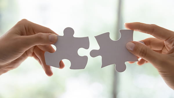 Two hands holding puzzle pieces