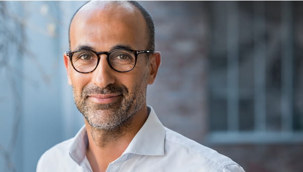 A middle-aged man, who is wearing glasses, is smiling.