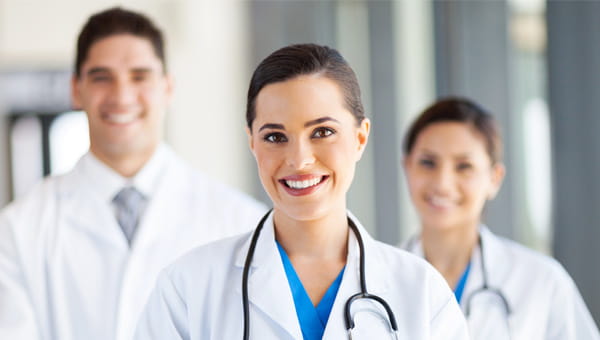 A diverse group of physicians smiles for a photo.
