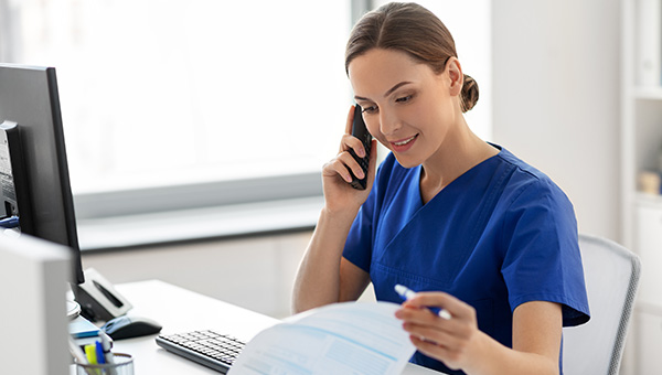 A nurse talking on the phone while looking at a patient's chart.