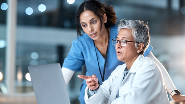 A physician and nurse looking at a laptop screen.
