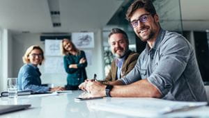 Happy group of businesspeople during presentation. Colleagues looking at camera and smiling