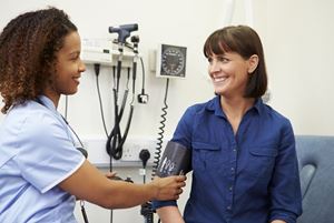 Nurse Taking Female Patient's Blood Pressure In Hospital