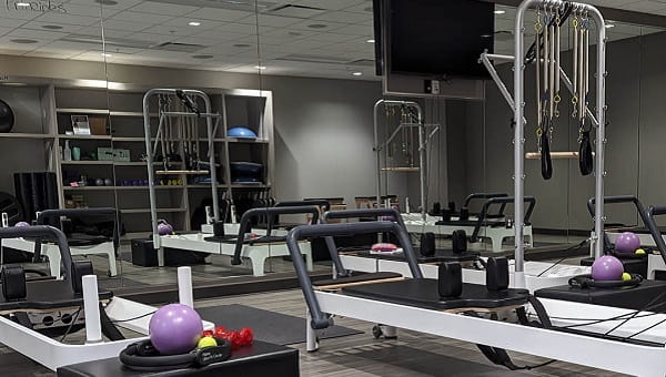 fitness center equipment neatly aligned against a wall of mirrors including weights and yoga mats