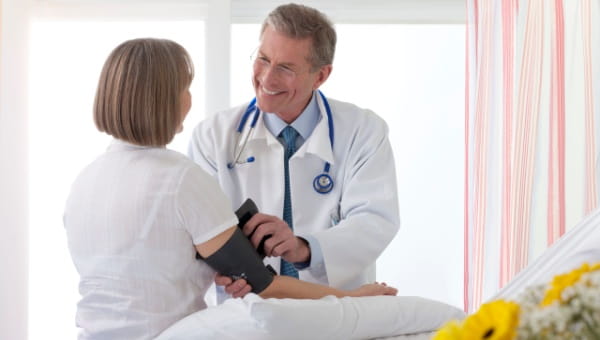 Smiling doctor taking the blood pressure of a patient
