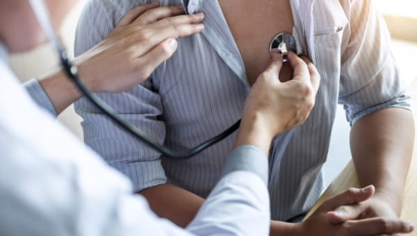 A doctor listening to a patient's heart through a stethescope.