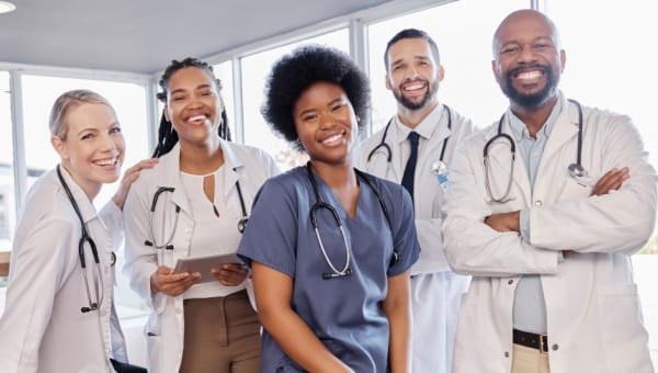 A group of four doctors and a nurse smiling.