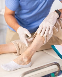 Person sitting on an exam table with physician pointing to the leg