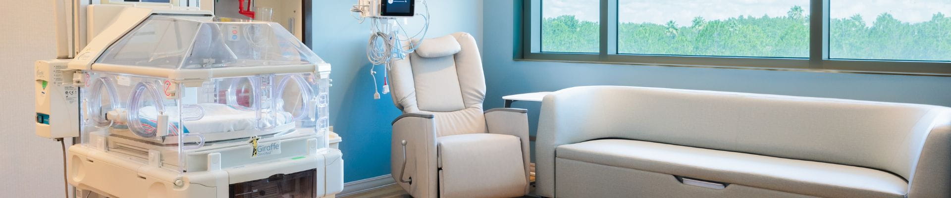 A hero image of a private NICU Room at the St Joseph's North Hospital, showing a chair, couch, and NICU Bed