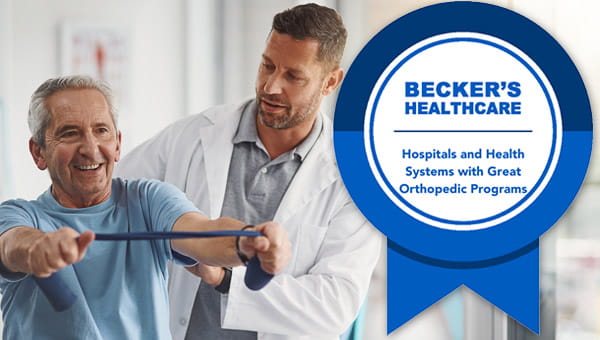 A physician oversees a patient stretching a resistance band with a logo to the side for Becker's Healthcare accreditation for health systems with great orthopedic programs.