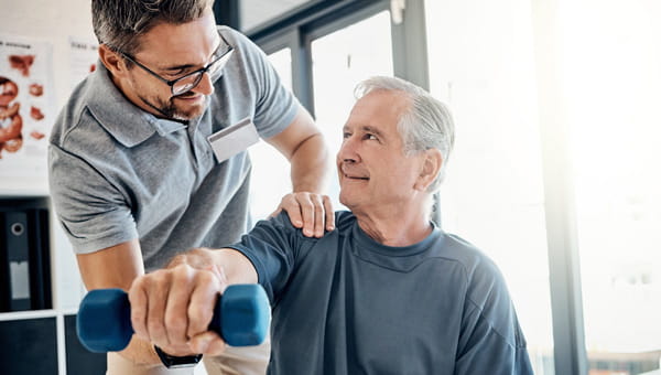Man working with a trainer lifting a light dumbell