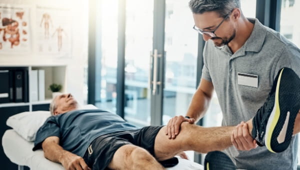 A physical therapist stretches a patient's leg.