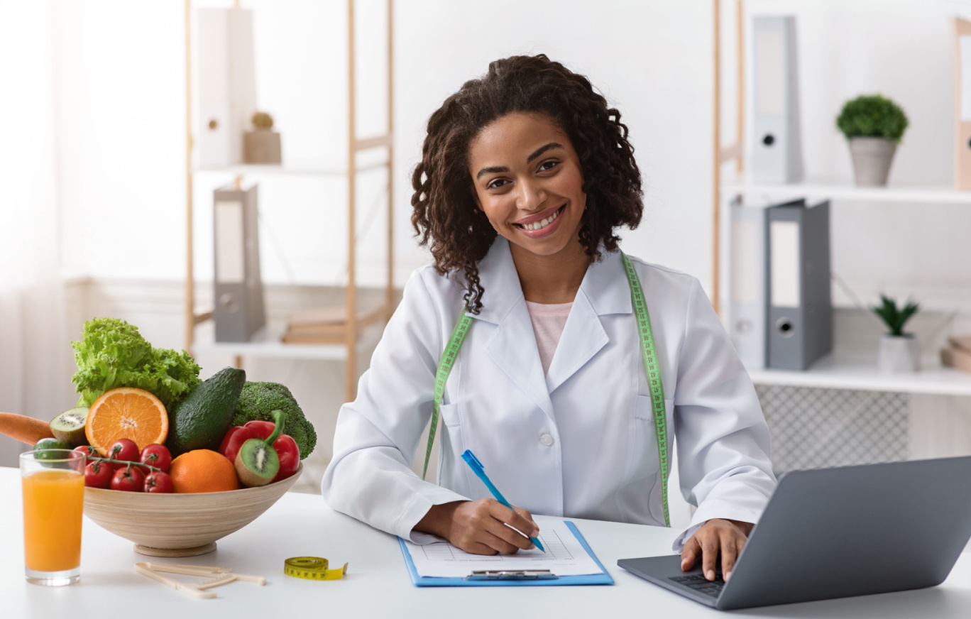 A woman nutritionist smiling by her desk in a professional setting
