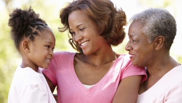 Grandma, Mom both smiling and looking at a young daughter.