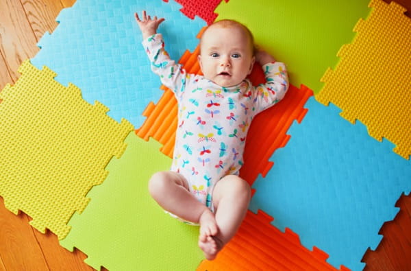 4 months old baby girl lying on colorful play mat