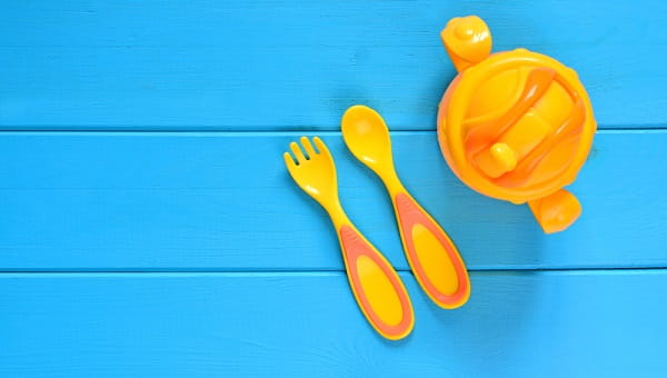 Children fork, spoon and feeding bottle on a wooden table