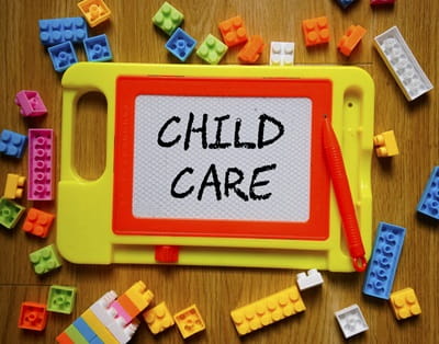 The words "child care" are written on a child's drawing board that is surrounded by toy building blocks