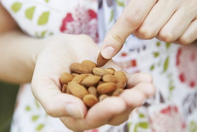 Close up of a woman eating a handful of almonds