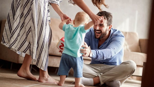 happy couple mother and father playing with a baby boy at home