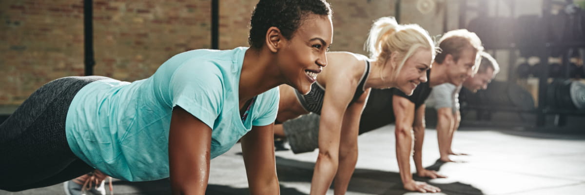 Group of active adults in a fitness setting planking together.