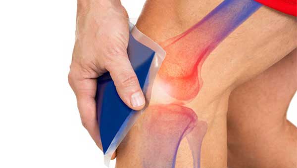 A hand holds an ice pack on a knee with the bones highlighted under the skin to show pain points. 