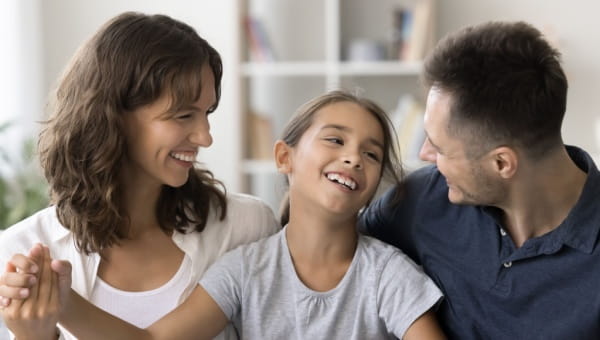 a photo of two parents hugging their daughter