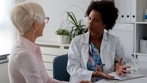 female physician speaking with elderly female patient in office
